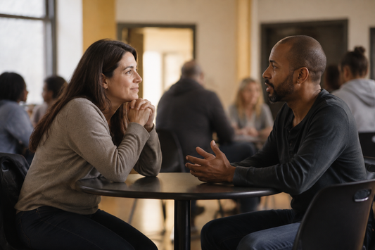 Two adults in a warm community setting having an attentive, equal conversation with a calm, respectful tone.