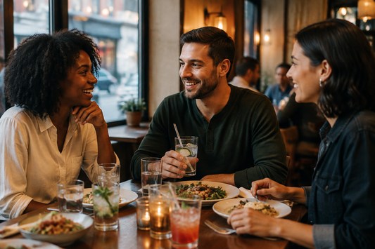 Friends enjoying dinner and conversation together without alcohol, with sparkling water and food in warm natural light.
