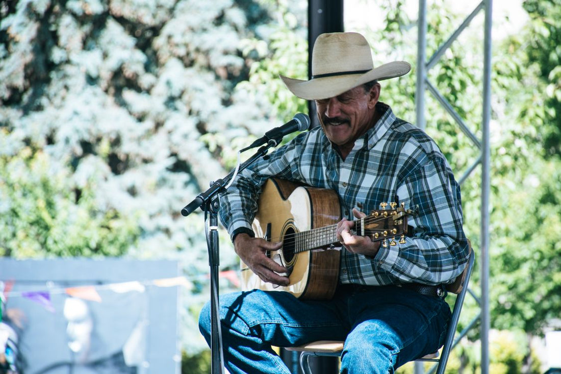 Country musician playing guitar on an outdoor stage; contextual stock image by Brett Sayles via Pexels. This image does not depict Tom Wolfe.