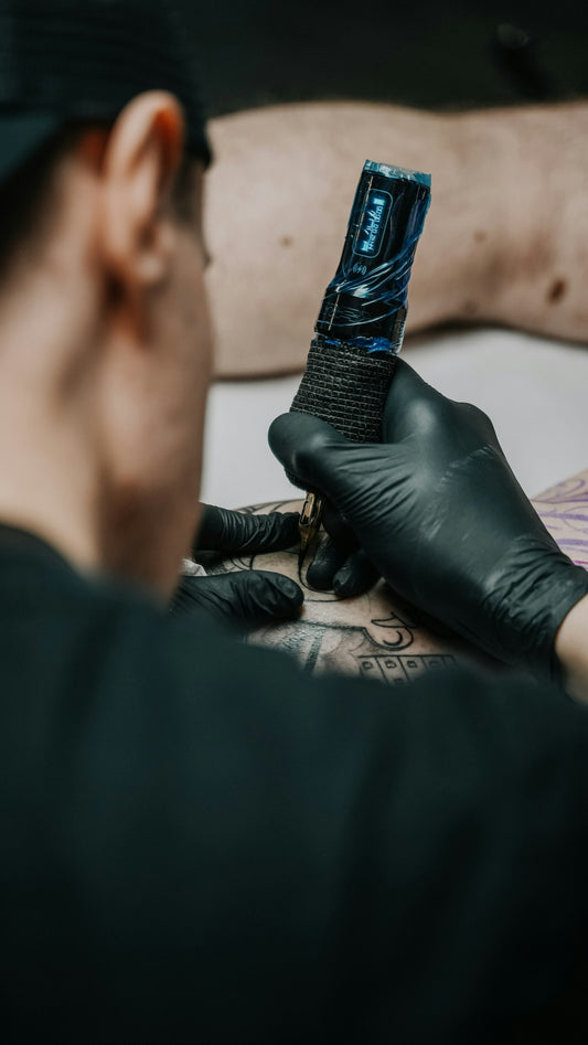 Tattoo artist working on a person's arm in a studio, illustrating sober tattoo ideas and recovery symbolism