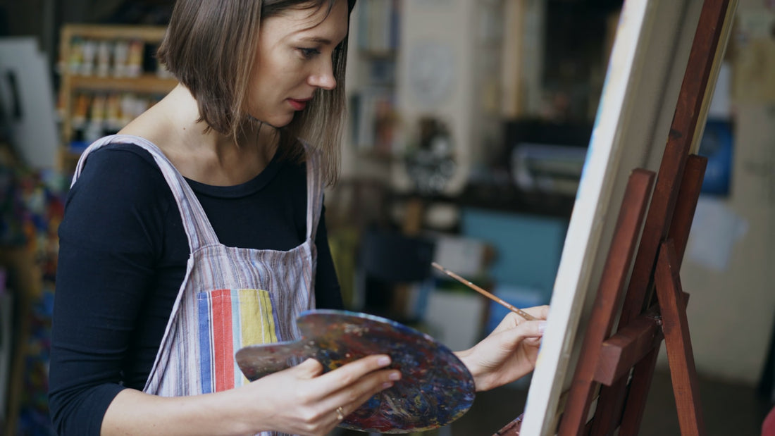 An artist painting on canvas in a studio