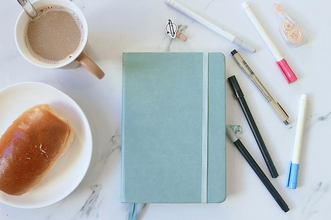 Notebook, coffee and pens on a table representing written recovery quotes and reflections